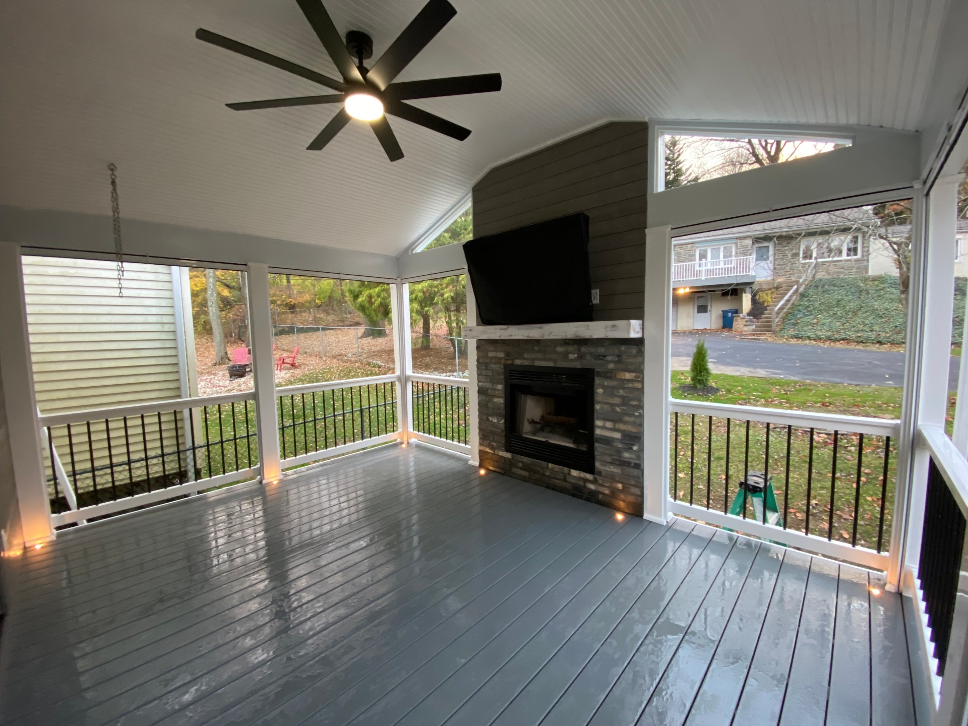 Screened porch with vaulted ceiling, fireplace, and mounted television