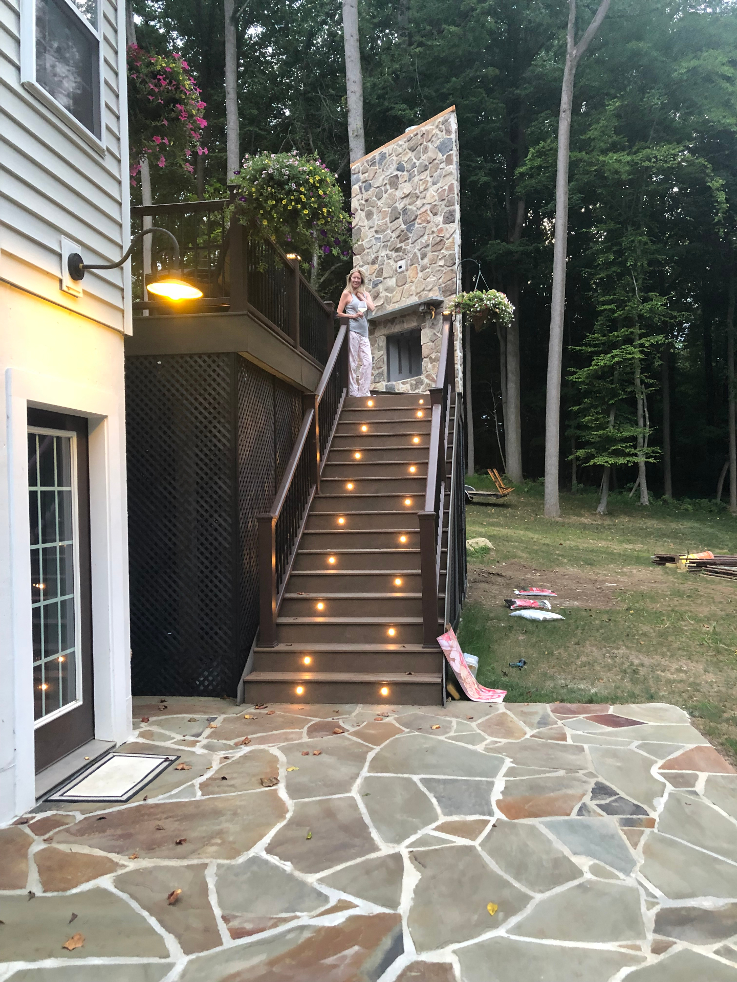 Stone patio with illuminated deck stairs and outdoor fireplace